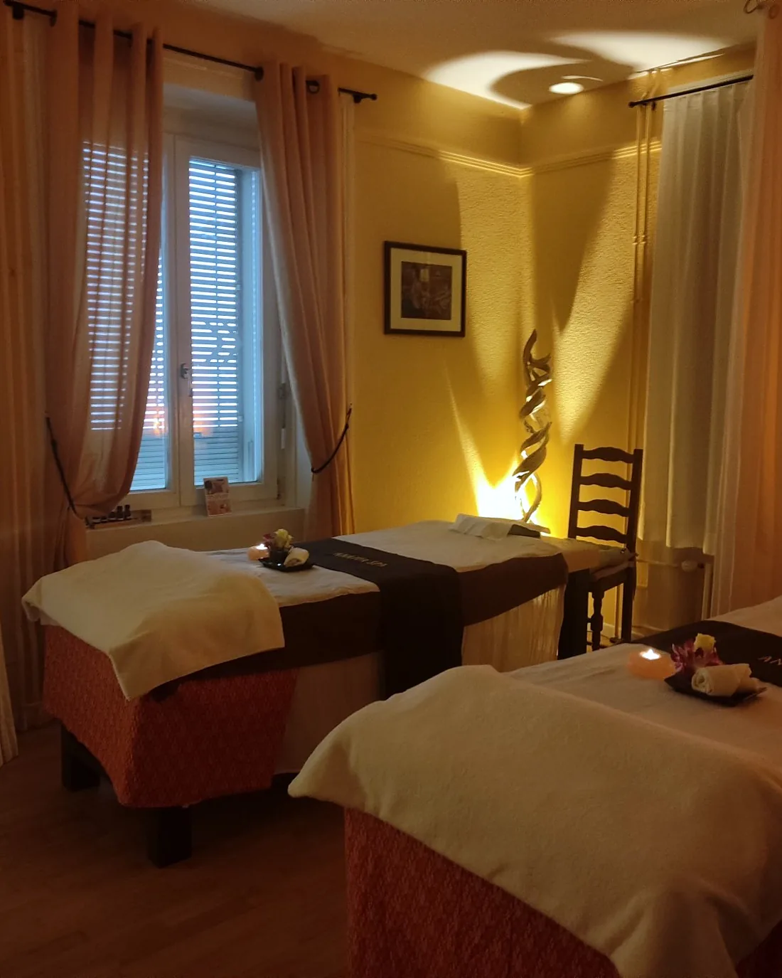 Warm beleuchteter Doppelraum mit zwei Massageliegen bei Anatta Spa